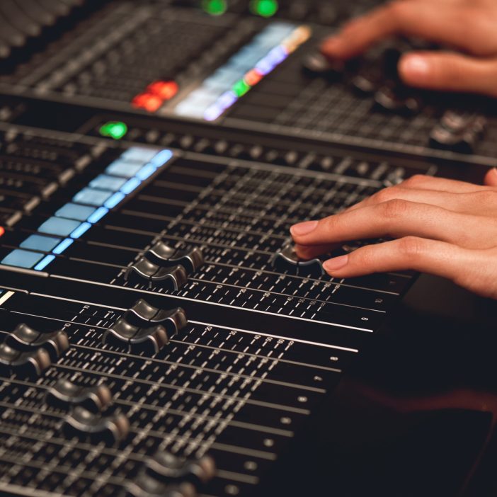 Audio system for professionals. Close-up view of sound engineer adjusting digital audio mixing console. Sound recording studio Service audio video