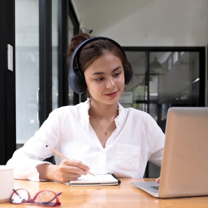 asian woman interpreter write translation from foreign language to english listen to audio record in headset. Interpretariato e traduzione