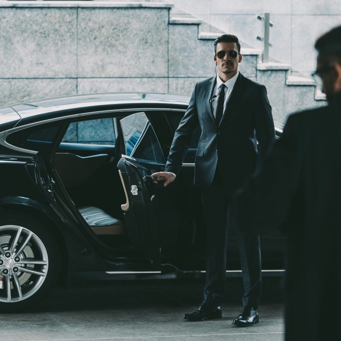 bodyguard in sunglasses opening car door to businessman Servizio bodyguard