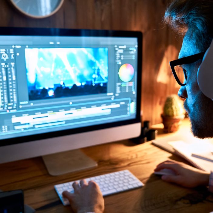 Male videographer editor using pc computer editing footage at home office. Servizio video